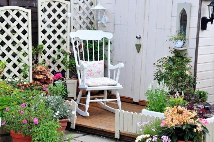 Farbenfrohe Gartendeko mit Schaukelstuhl in Weiß-Rückzugsort Gartengestaltung mit Topfpflanzen Schaukelstuhl aus Holz
