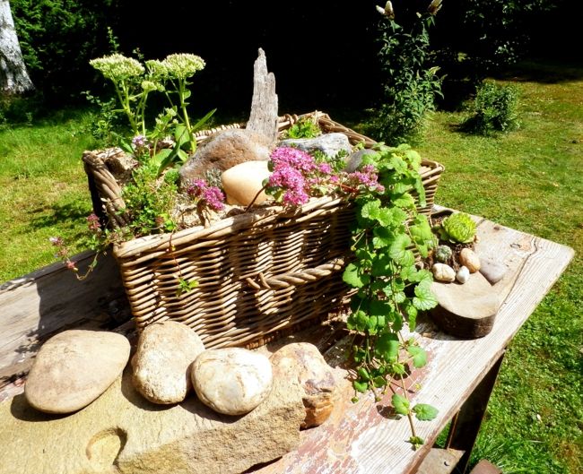 Wooden garden table with a large flower basket and stones as a decoration Garden decoration - ideas