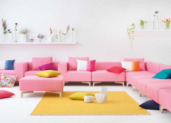 modulare Sofas in Rosa, gelber Teppich, bunte Dekokissen-Einrichtungstrends
