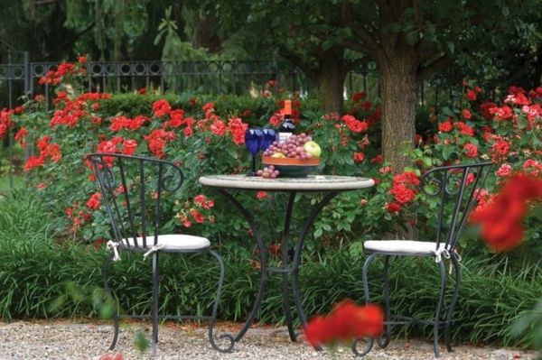 rote Gartenmöbeln umgeben von bezaubernd duftenden Rosen