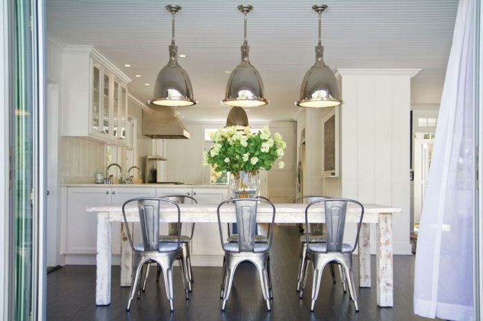 White flowers on the white table complete the overall picture of this stylish kitchen