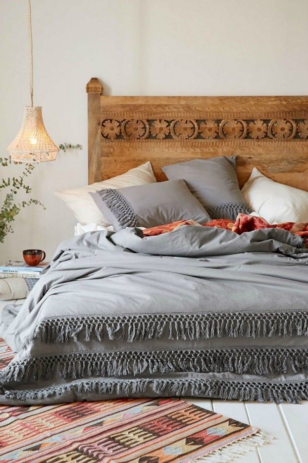 Headboard made of wood in bohemian style. Hanging lamp bed linen in gray