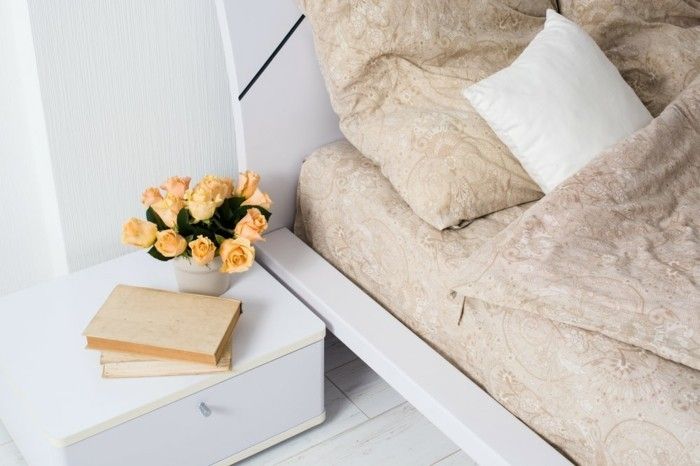 stylish-and-cozy-furnished-beige-bedding-flowers-on-the-bedside-table