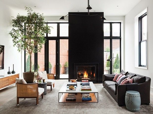 black-fireplace-wall-black-window-frames-black-couch-light-wall-color-light-carpet-wood-furniture-green-in-the-room