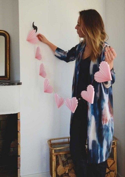 junge Frau dekoriert den Raum mit rosa herzen aus Papier