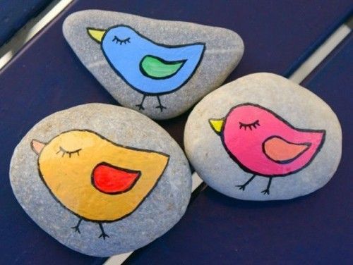 drei kleine bunte Vögel malen auf Steine 