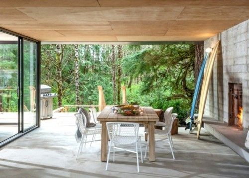Ideen für Betonboden überdachte Veranda Steinwand Kamin Esstisch Stühle