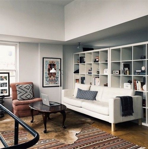 Weißes Regal hinter Sofa Wohnzimmer Teppiche Sessel Wandbild Kaffeetisch Laptop