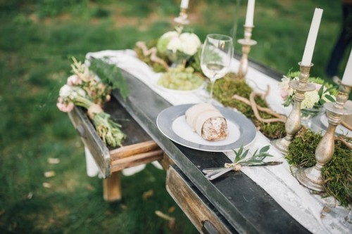 Hochzeitstisch mit Tellern Messern und Gabeln Kerzen Moos Grün und Brot dekoriert