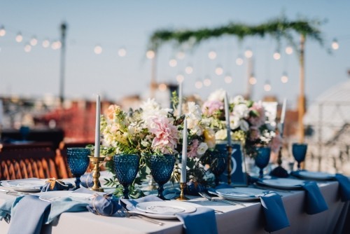 Lange Tische mit grauen und blauen Tischdecken mit Porzellan und blauen Gläsern serviert und reich verziert