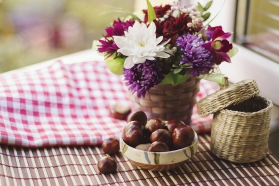Mit Kastanien basteln in einer Schale auf dem Tisch mit schönen Herbstblumen kombinieren