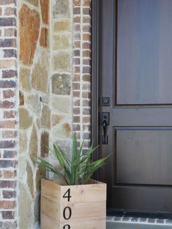 Pflanzkübel aus Holz zeigt die Hausnummer vor der Tür