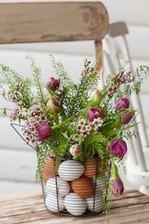 Blumendeko zu Ostern Ein Korb mit Eiern und Grün und rosa Blüten darauf