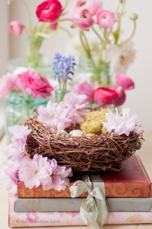 Blumendeko zu Ostern ein Nest mit rosa Blüten und bunten Eiern Ostern Mittelstück
