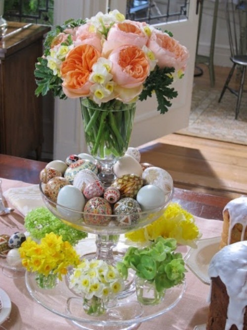 Blumendeko zu Ostern ein Ständer aus Glasschalen mit winzigen Frühlingsblumenarrangements bunte Eier und rosa Blüten