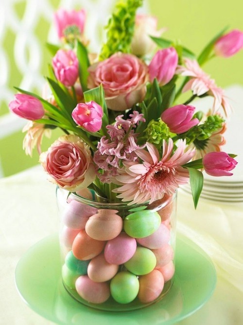 Blumendeko zu Ostern ein hellrosa Blumengesteck in einem Glas mit bunten Eiern