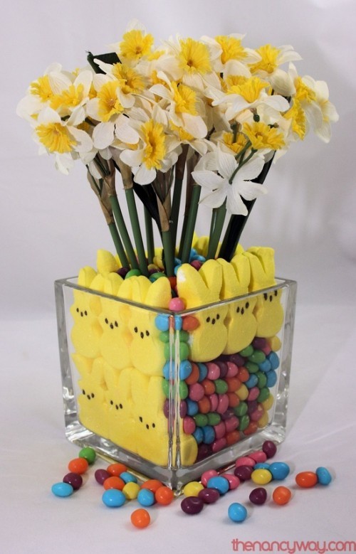 Blumendeko zu Ostern eine Vase aus klarem Glas mit gelben Hasen Süßigkeiten gelbe Narzissen