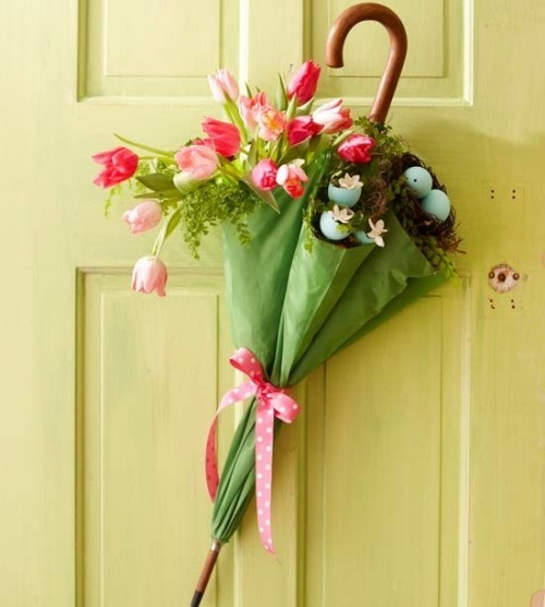 Blumendeko zu Ostern grüner Regenschirm gefüllt mit rosa Tulpen und ein Nest mit blauen Eiern