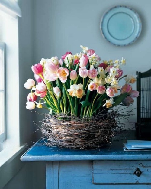 Blumendeko zu Ostern üppiges Blumenarrangement aus rosa Tulpen und weißen Narzissen in einem Nest