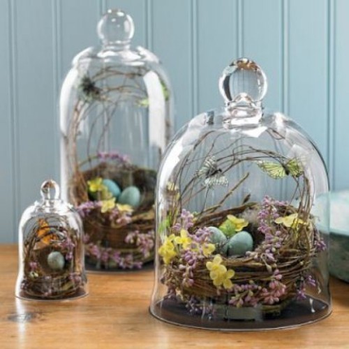 Rustikale Osterdeko Nester mit Ostereiern und Frühlingsblumen unter Glasglocken