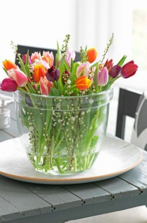 Wunderschöne Blumenarrangements farbenfrohe Tulpen im Glasbehälter auf dem Esstisch