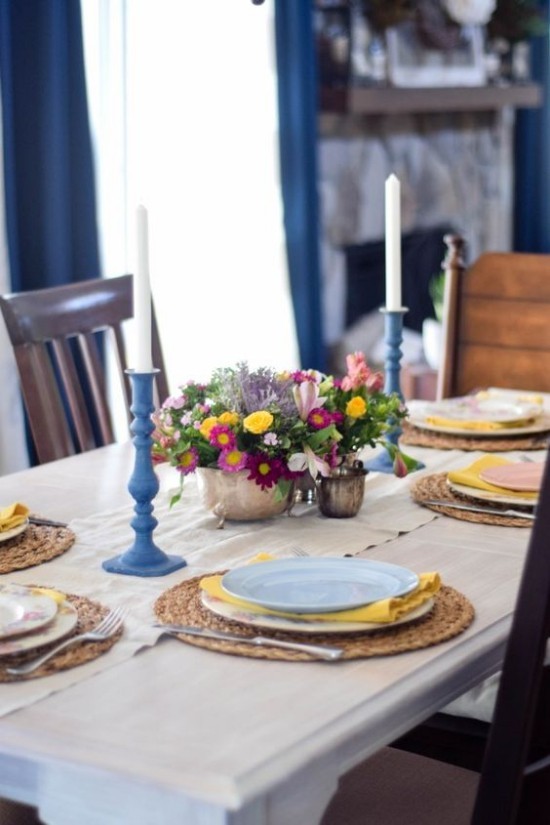 frühlingshafte Tischdekoration blaue Kerzenhalter farbenfrohe Blumen in Vasen