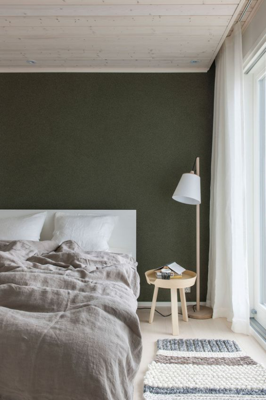 Schlafzimmer Ideen im Scandi Style Pastellfarbe Dunkelgrün an der Wand hinter dem Schlafbett weiße Lampe in der Ecke