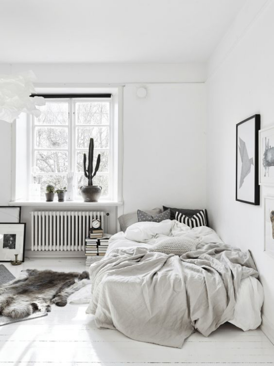 Schlafzimmer Ideen im Scandi Style Weiß Grundfarbe weiches Fell auf dem Boden gestreiftes Kissen schwarz weiß immergrüne Topfpflanze