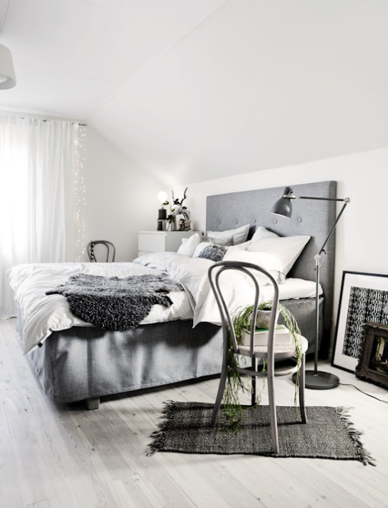 Schlafzimmer Ideen im Scandi Style großes komfortables Bett in Grau Stuhl mit Kranz aus grünen Weidenzeigen Lampe Bilder Fell Dekoration