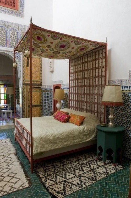 Marokkanisches Schlafzimmer handgewebte Stoffe über und am Schlafbett Teppiche Mosaik an der Wand bunte Deko Kissen