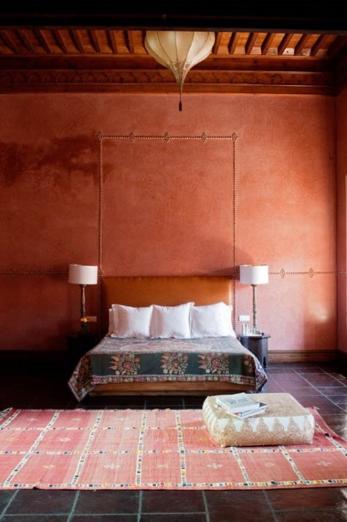 Marokkanisches Schlafzimmer in warmen Farben schön gemusterter Teppich ein quadratischer Sitzhocker darauf