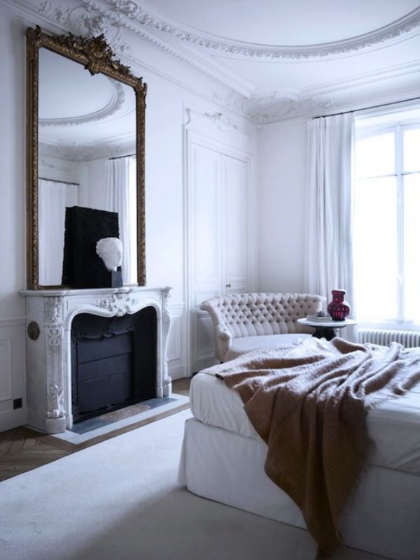 Parisian chic in the bedroom, fireplace, high wall mirror, comfortable upholstered sofa, large sleeping bed, decorative item