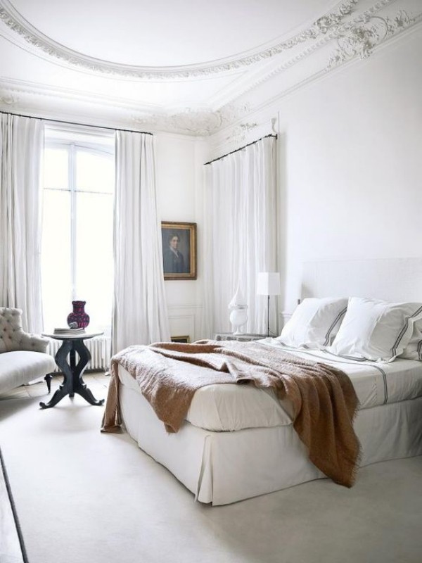 Pariser Chic im Schlafzimmer helles Ambiente Charme und Stil Wandgemälde Wurfdecke auf dem Schlafbett Sessel kleiner Tisch
