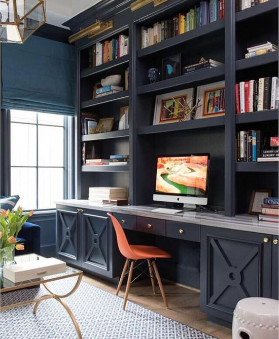 Farben fürs Heimbüro dunkelblaue Bücherwand PC viele Bücher in bunten Farben Vase mit Tulpen Stuhl in Koralle