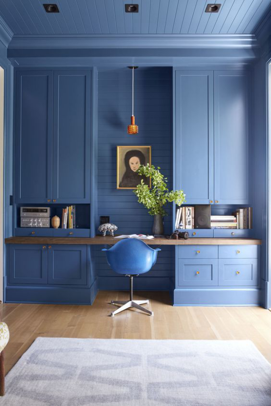 Farben fürs Heimbüro sehr stilvolle Einrichtung und Raumgestaltung in sanftem Blauton Bücherschrank in Blau Wandbild blauer Stuhl hellgrauer Teppich