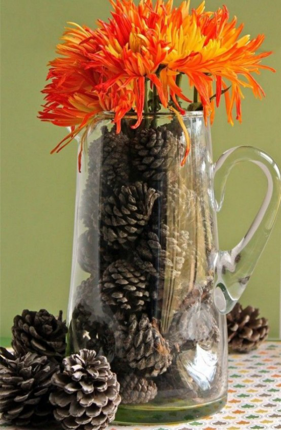 Herbstdeko mit Tannenzapfen Glaskanne mit Zapfengefüllt und mit Herbstblumen geschmückt