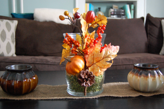 Herbstdeko mit Tannenzapfen Vase aus Glas herbstlich dekoriert auf dem Kaffeetisch