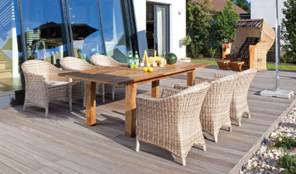 Hochwertige Gartenmöbel ganzes Set Sessel aus Polyrattan Esstisch aus massivem Holz Strandkorb im Hintergrund
