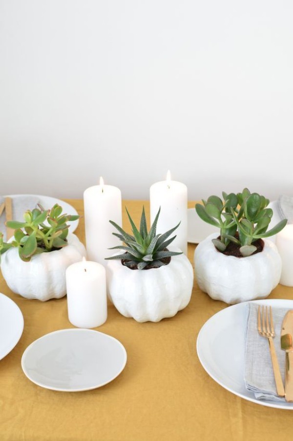 Skandinavische Herbstdeko zu Hause Sukkulenten in weißen Töpfen weiße Kerzen Geschirr auf dem Esstisch