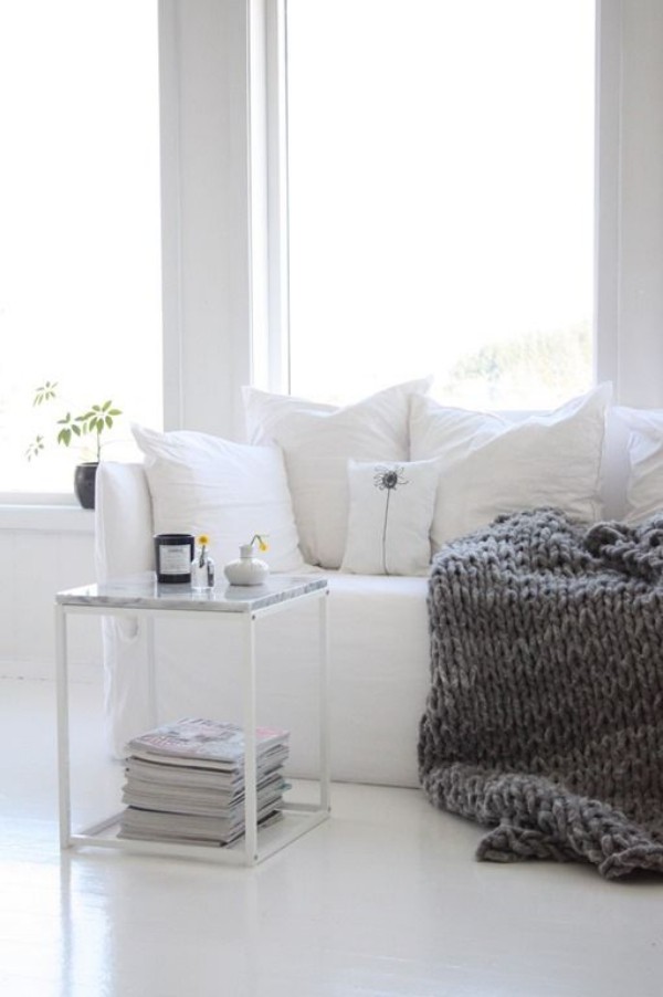 Skandinavische Herbstdeko zu Hause skandinavisches Interieur in Weiß graue gestrickte Wolldecke auf dem Sofa kleine Deko Elemente