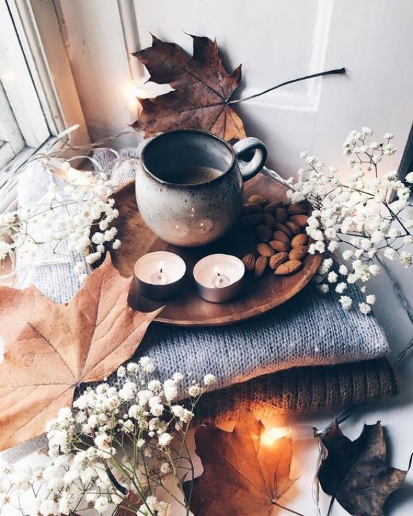 Skandinavische Herbstdeko zu Hause strahlt Wärme und Gemütlichkeit aus weiße Ziergräser Blätter Mandeln Teelichter wollene Pullover oder Überwurfdecken