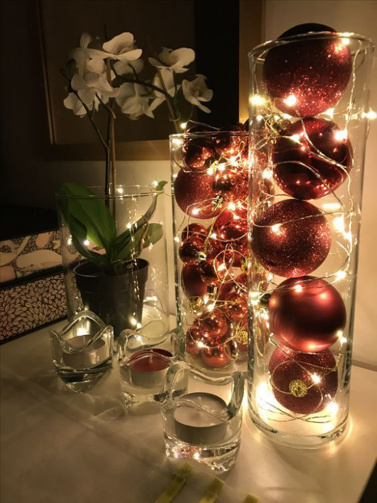 Christbaumornamente als Raumdeko dunkelrote Weihnachtskugeln in Glas Kerzen weiße Orchidee
