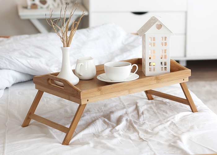 Holztablett mit Kaffee und Innendekor auf dem Bett mit weißer Bettwäsche