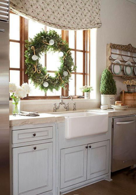 Küche zu Weihnachten schmücken großer grüner Kranz am Fenster weiße Kugeln weiße Chrysanthemen in Vase