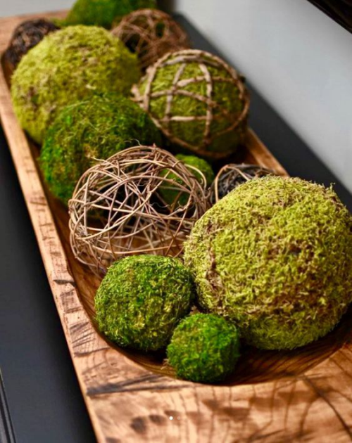 Frühlingsdeko mit Moos grüne Bälle auf einem Holztablett