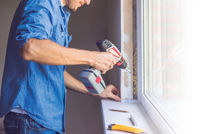 DIY Handwerken Mann beim Bohren Fensterrahmen erneuen verdichten