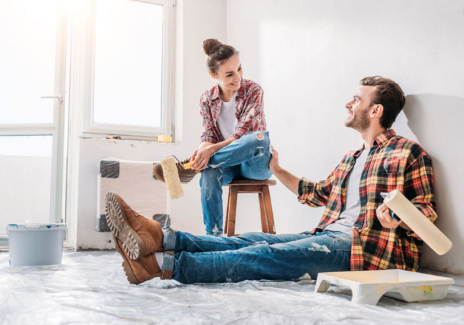 DIY Handwerken zu zweit Wände streichen mit Rolle junger Mann und Frau Spaß haben