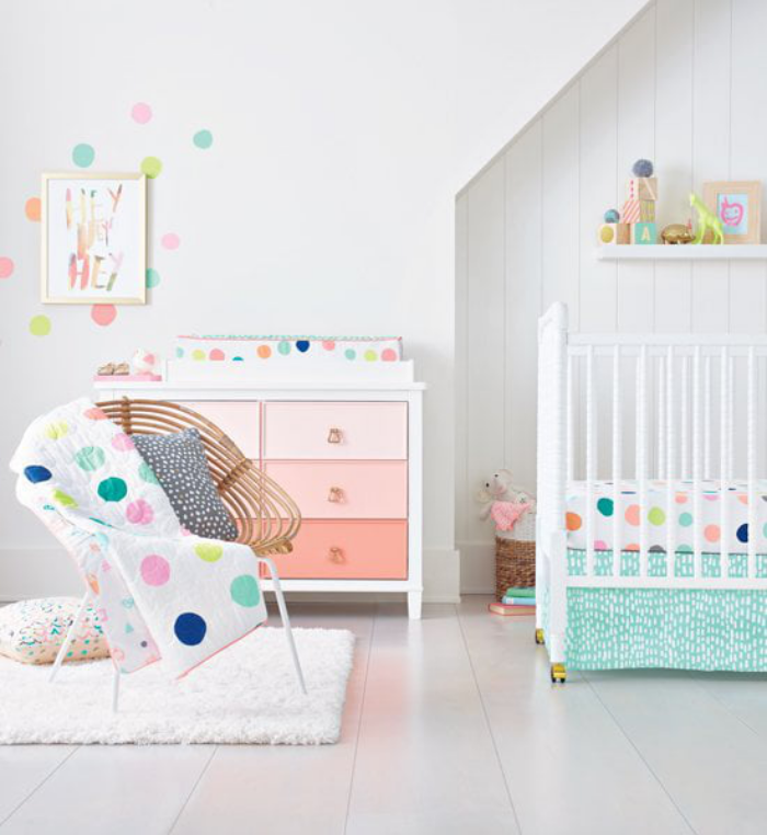 Kinderzimmer Babyzimmer sehr gemütlich in Weiß und Pastellfarben kleine grelle Akzente gemusterte Wand Sessel Kommode in Pastellrosa