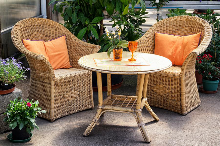 Gartenmöbel reinigen schöne bequeme Outdoor Sitzecke zwei Sessel aus Rattan runder Tisch viel Grün rundherum