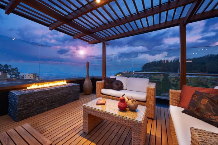 Moderne Terrassengestaltung trendige Einrichtungsideen Feuerstelle schicke Korbmöbel weiche Kissen Holzterrasse Beleuchtung
